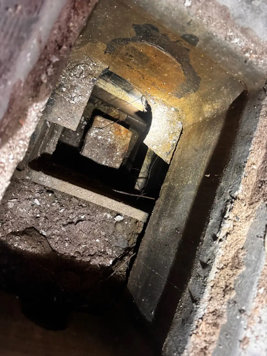 Looking down through an access opening at a rusted cast iron backwater valve body