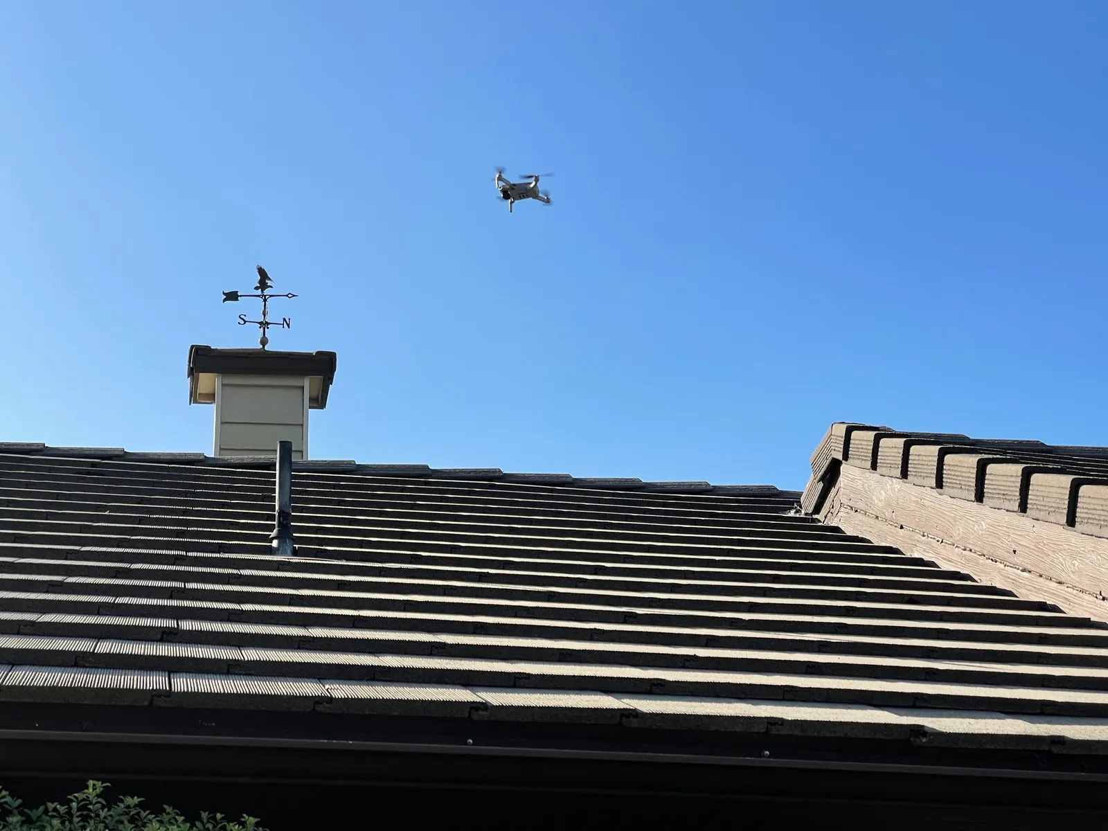 Inspection drone flying above a tile roof