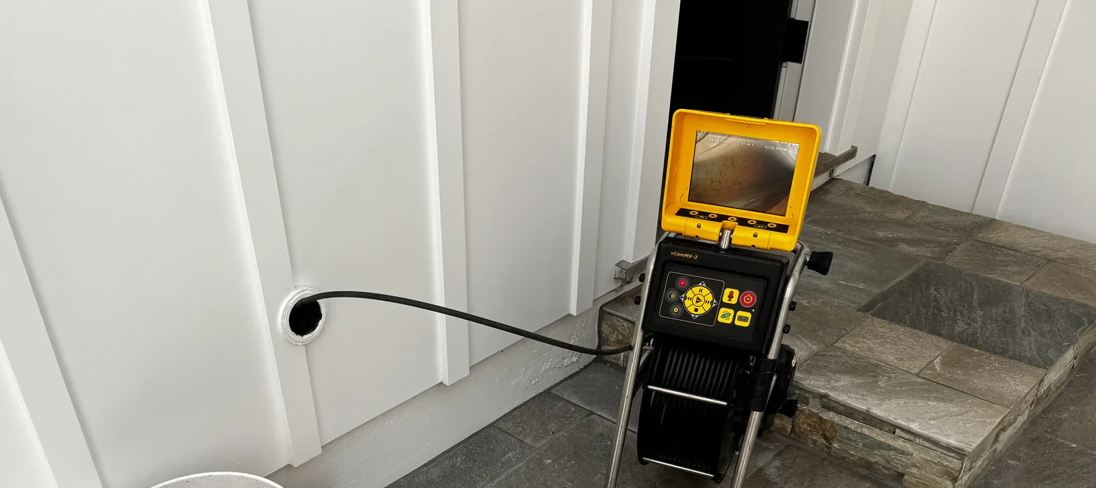 Sewer camera reel and monitor set up at a cleanout, with the camera feeding into the line